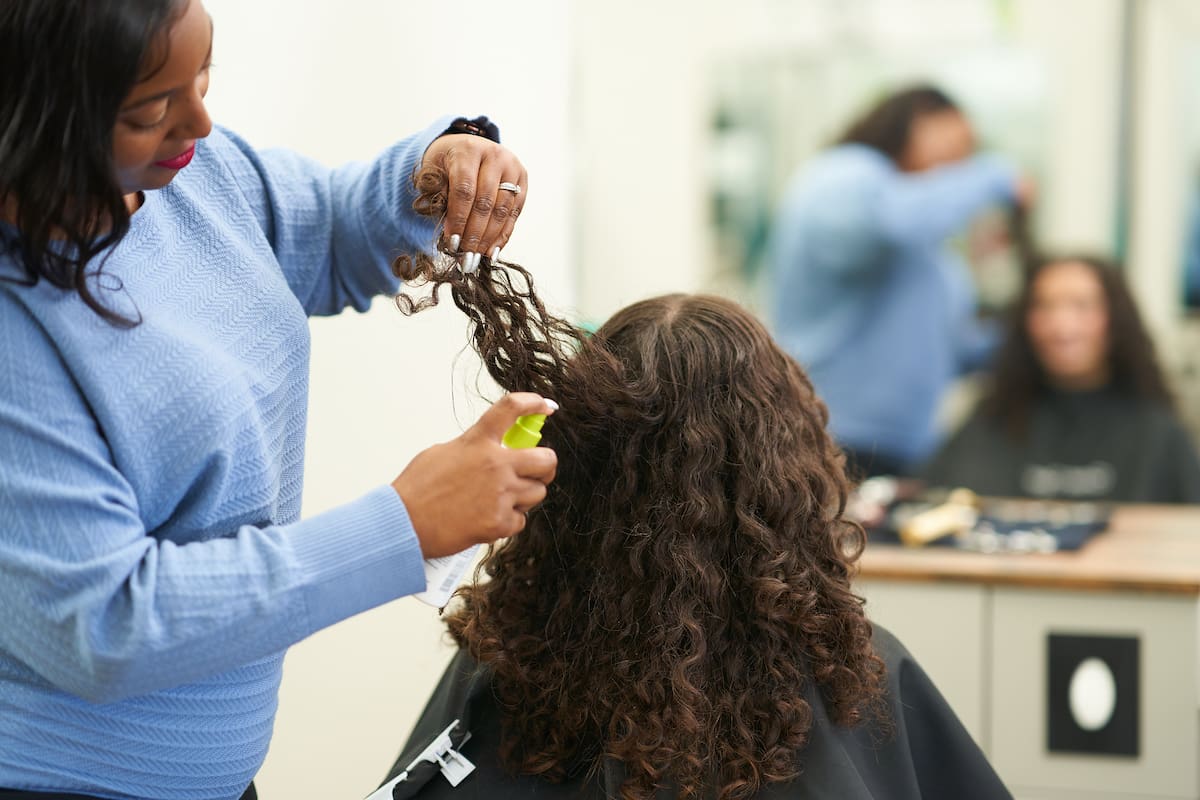 Great Clips stylist applying product to the back of a female's hair