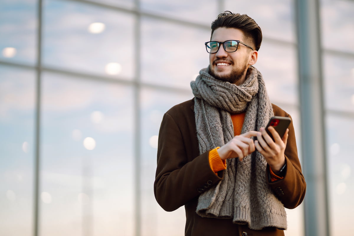 A man wearing a scarf while on his phone