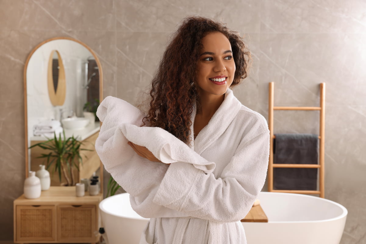 woman with curly hair towel drying her hair in bathroom woman with curly hair towel drying her hair in bathroom